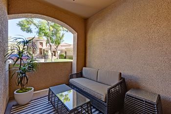 a patio with a couch and a table and a potted plant